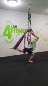 image of a woman doing dancer pose in an aerial yoga class